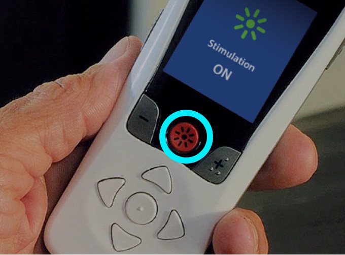 Person holding remote with the center red button highlighted