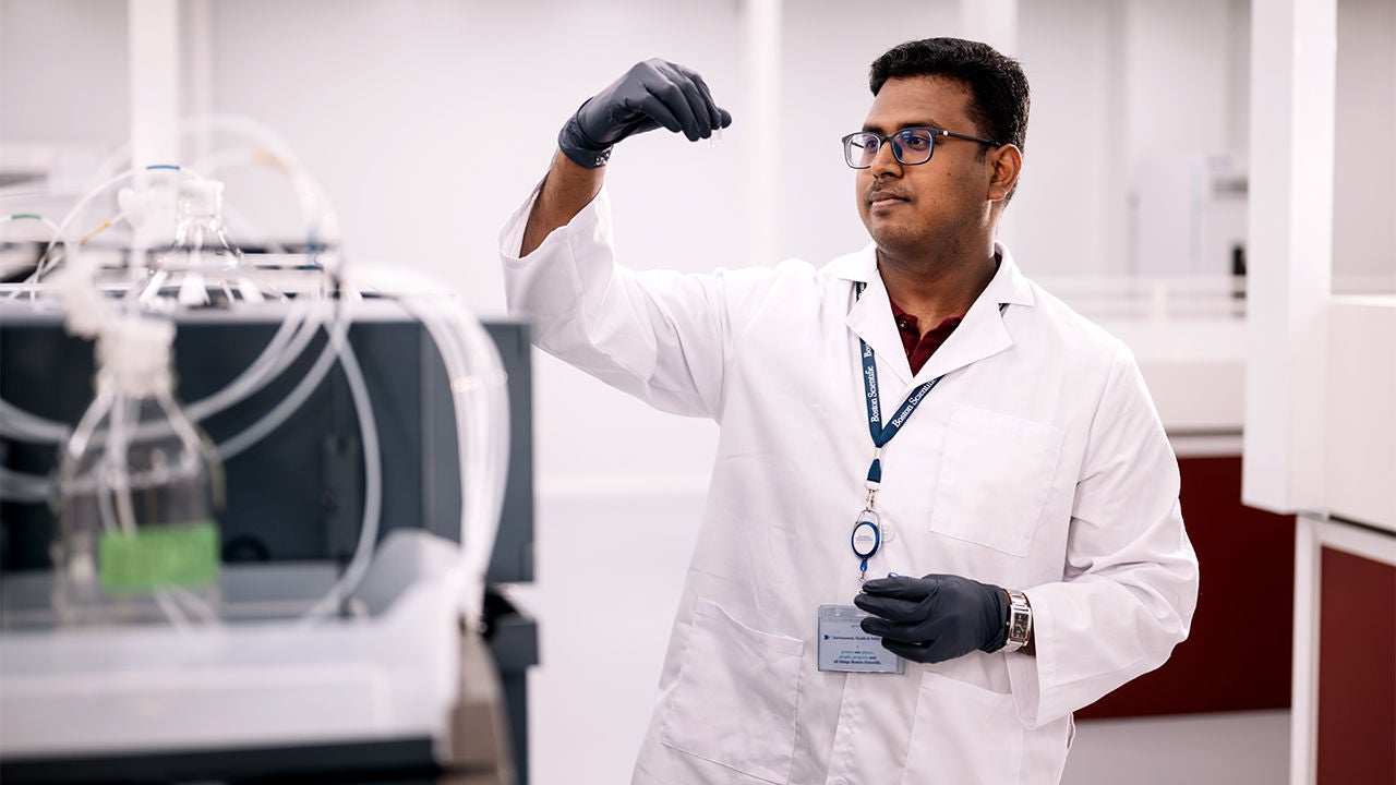A woman and a man wearing Boston Scientific lab coats talk to each other.