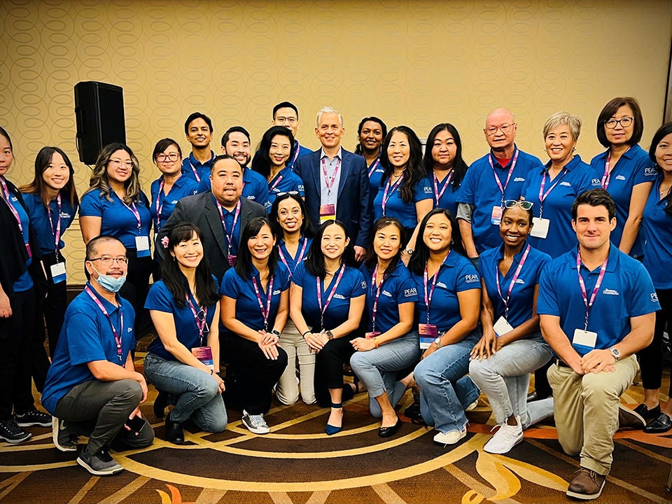A team of Boston Scientific employees wearing matching blue polos poses for a picture together at the National Association of Asian American Professionals conference.