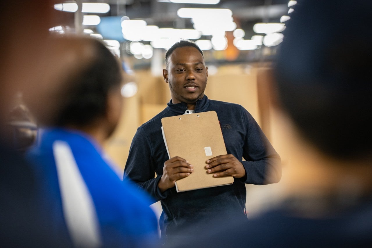 Young leader holding a folder and smiling at colleagues 