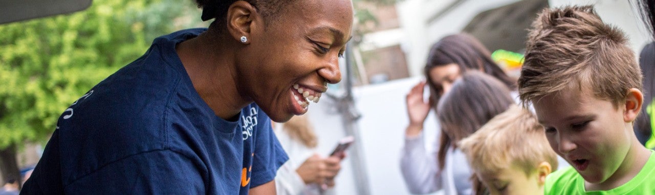 Healthcare professional wearing scrubs and a mask smiles into the camera.
