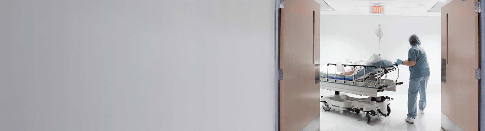 Healthcare professional transporting a patient in a hospital bed.