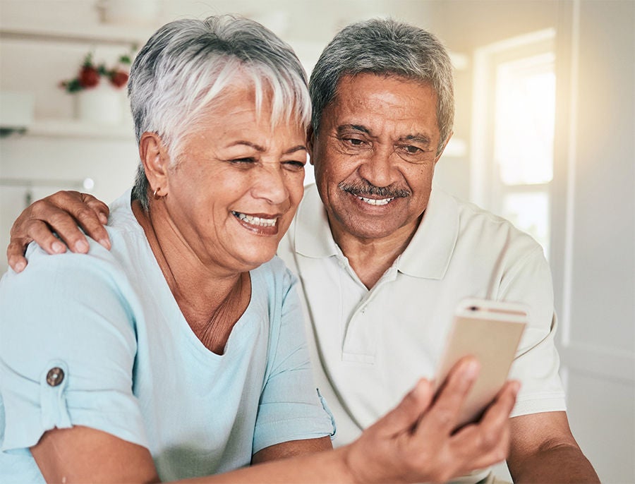 Smiling face of old couple looking toward phone.