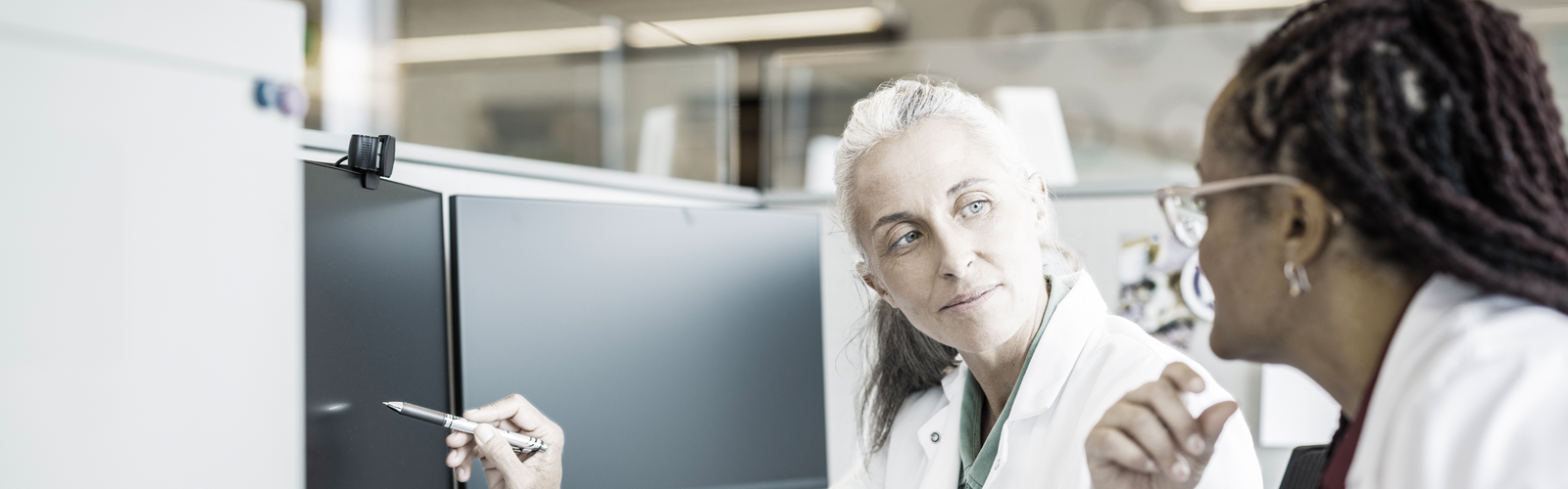 Woman physician and nurse looking toward computer screen.