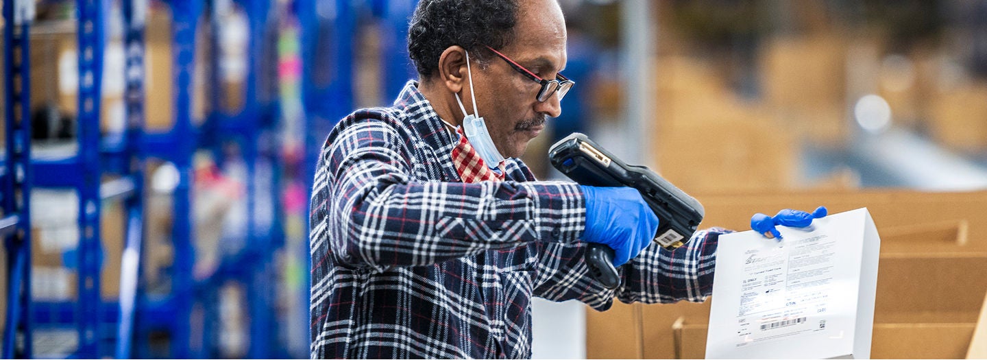 Warehouse worker scanning package with scanner.