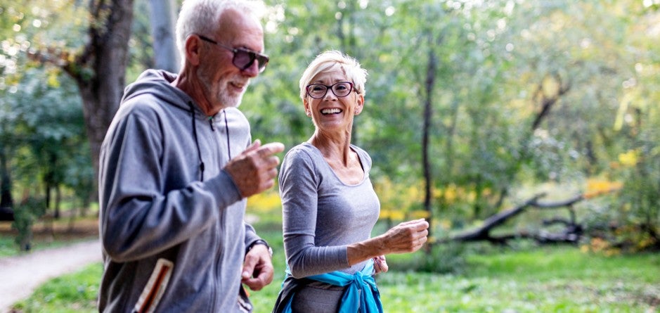 An eldery couple walking together in a park and smiling.