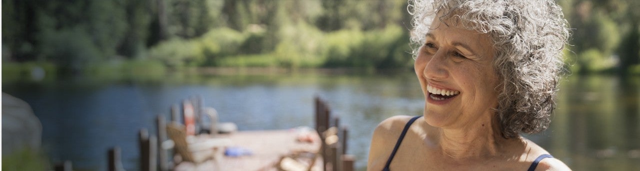 Woman in bathing suit laughing on a dock at a lake