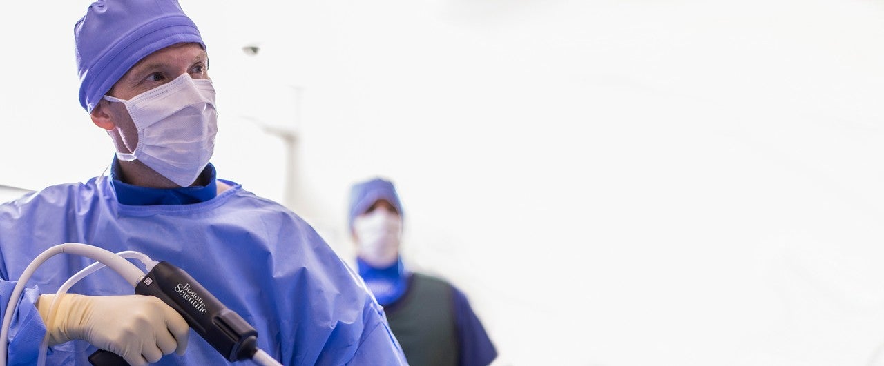 Surgeon in the OR holding stone device.