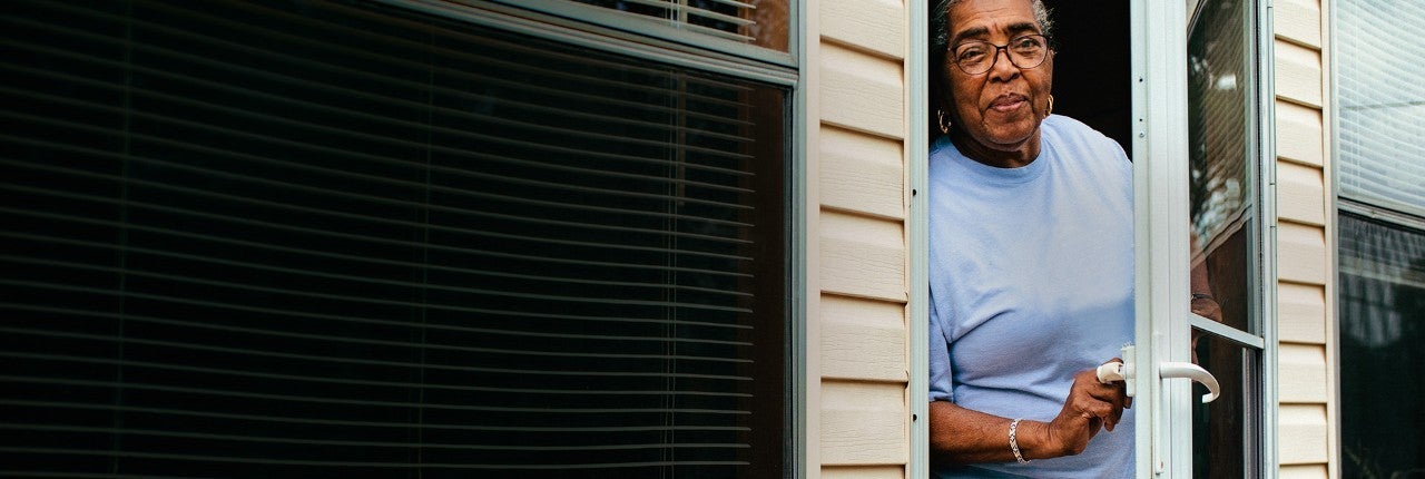Woman answering door of yellow home.