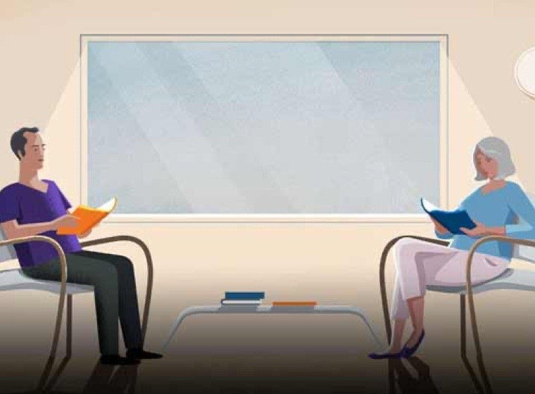 Two people sitting in chairs and reading