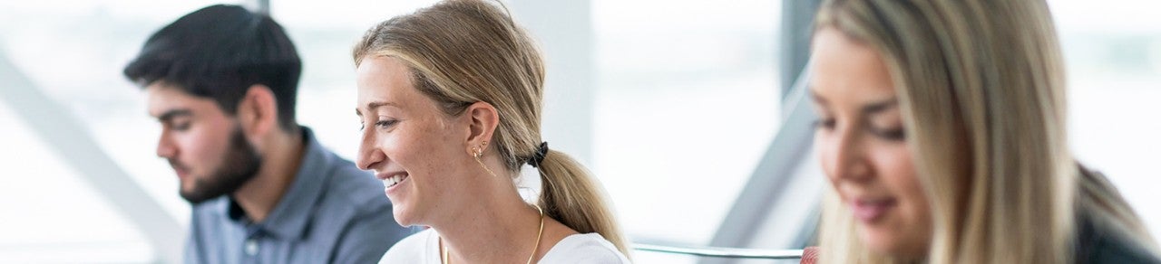 group of three employees working on laptop with smilimg faces