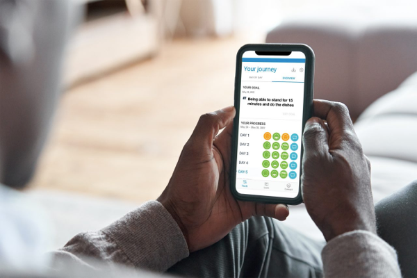 Hands using mobile phone with mySCS, to prepare patient for spinal cord stimulation.