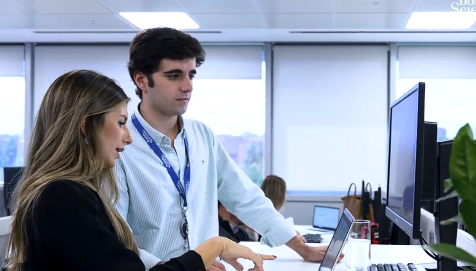 Empleado y empleada de Boston Scientific en España conversan frente a un ordenador en la oficina de Madrid