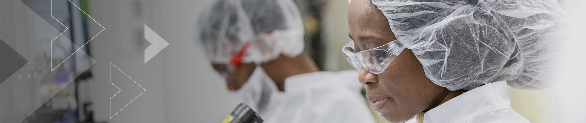 Healthcare professional wearing scrubs looking in microscope.