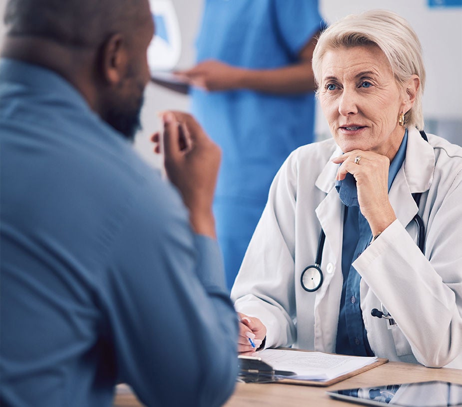 Mature medical professional consulting man in hospital for analysis.