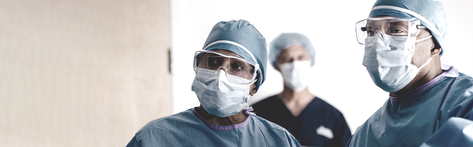 Group of three doctors in mask looking toward screen.