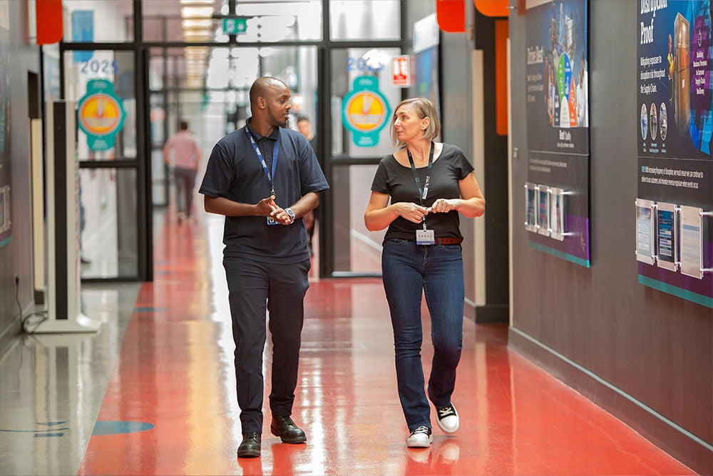 Employees walking through a manufacturing facility corridor.