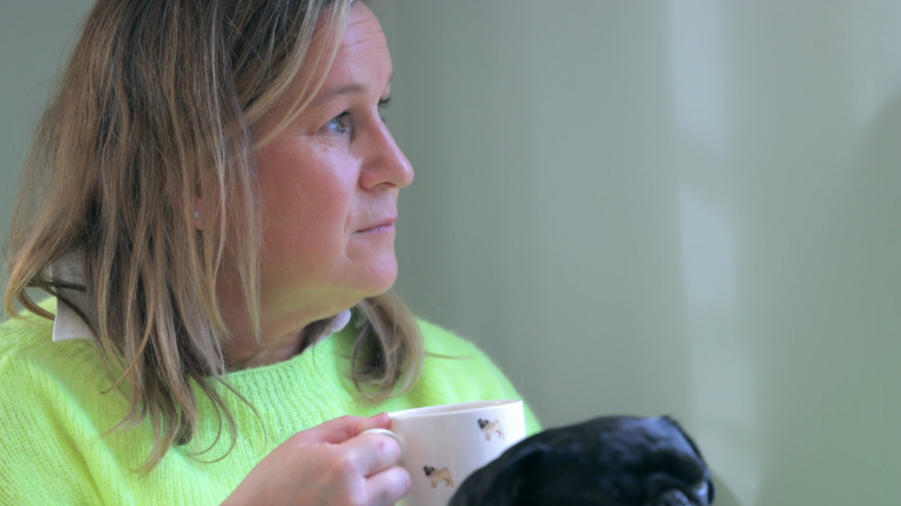 Woman holding a cup while looking out the window