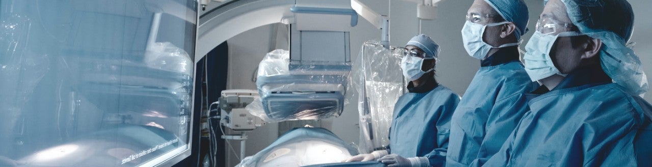 three doctors looking at a screen in a hospital room