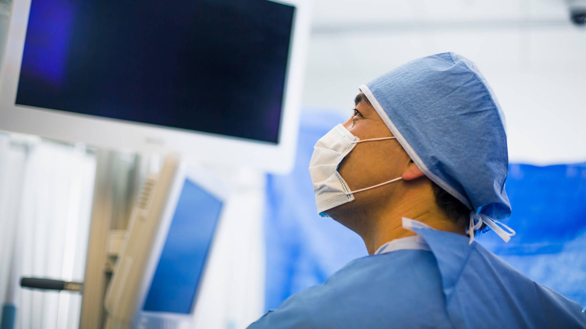 Surgeon in surgical attire viewing monitors during a urology procedure 