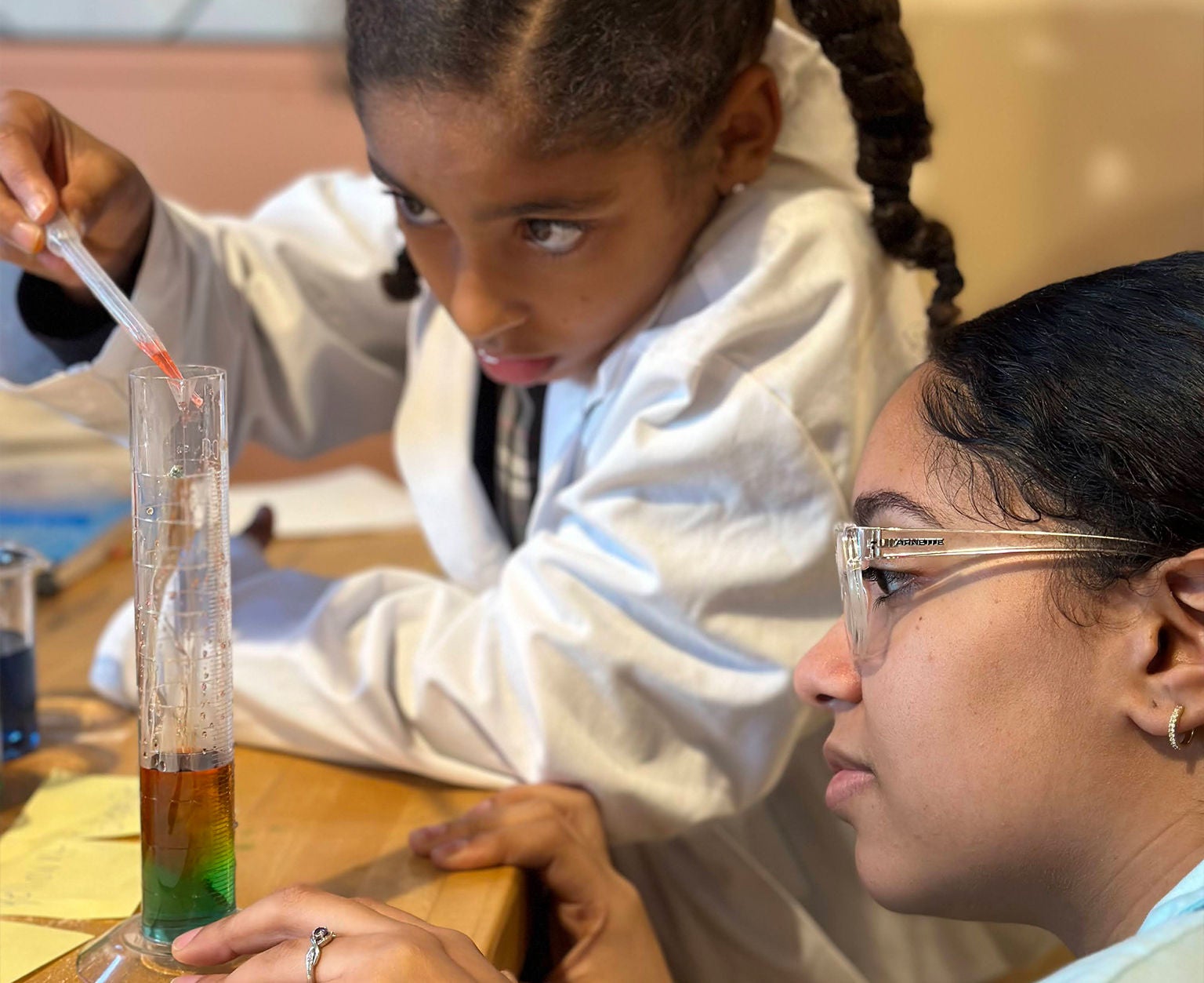 Two young girl in lab coat doing science project inside lab.