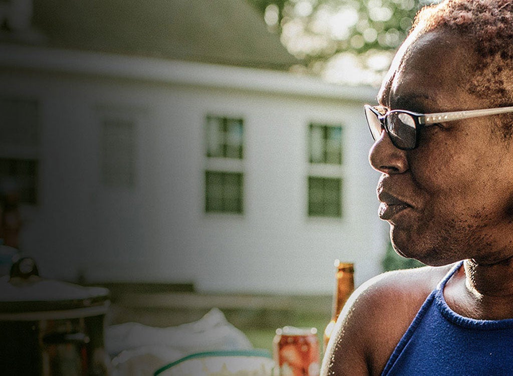 Woman wearing glasses and blue shirt standing in front of house.