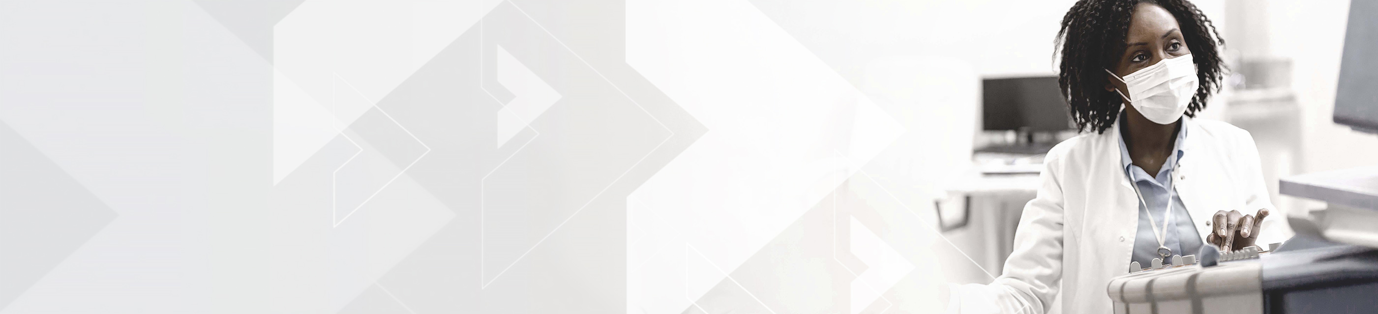 Healthcare provider wearing mask working at medical device console.