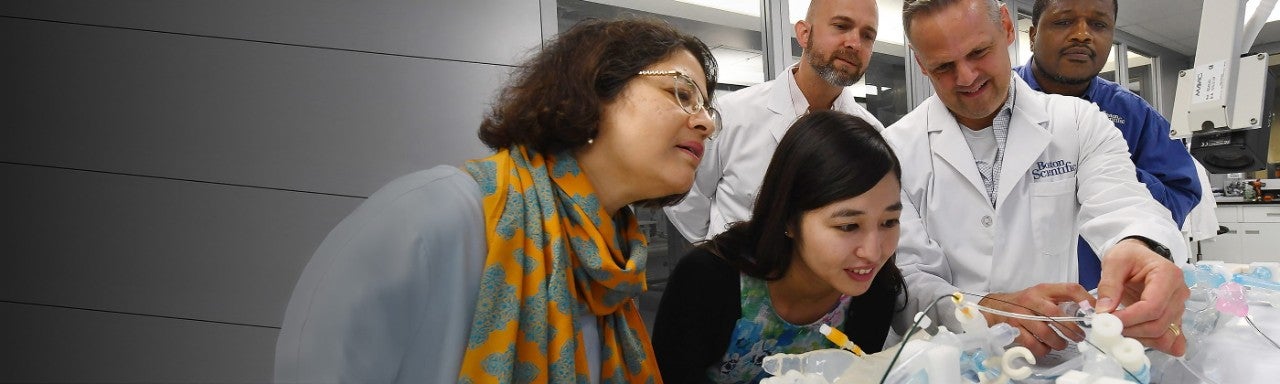 Five people at the Boston Scientific Innovation Center smiling and engaging with new technology.
