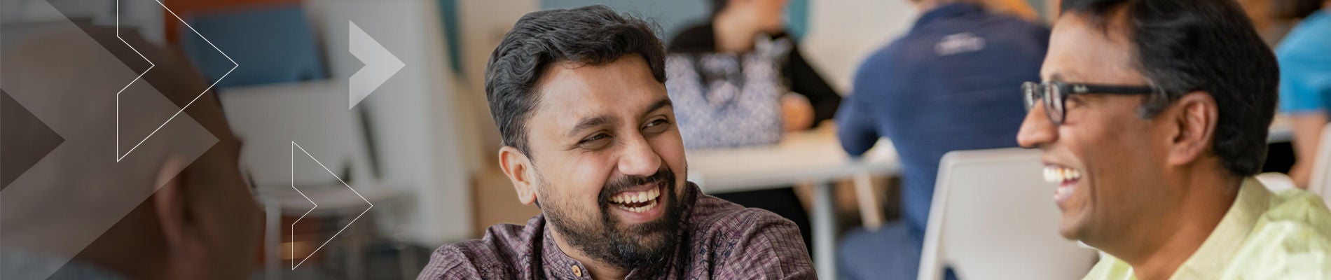 Man in business casual clothing smiles with his colleagues.