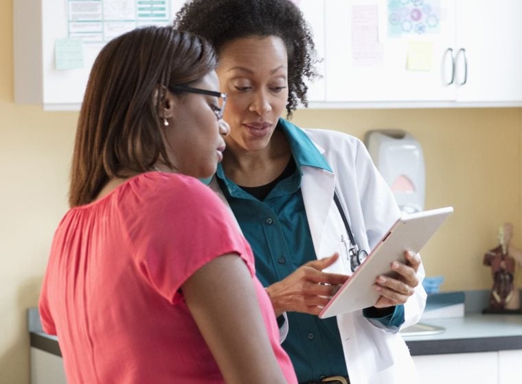 Woman and her doctor speaking and reviewing material on a clipboard