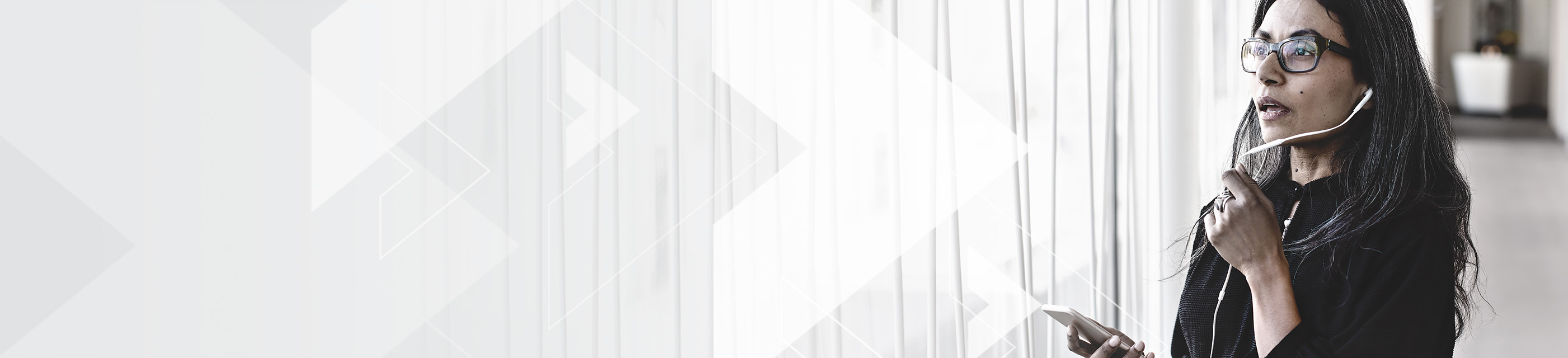 Businesswoman with glasses speaking into cellphone earbud microphone.