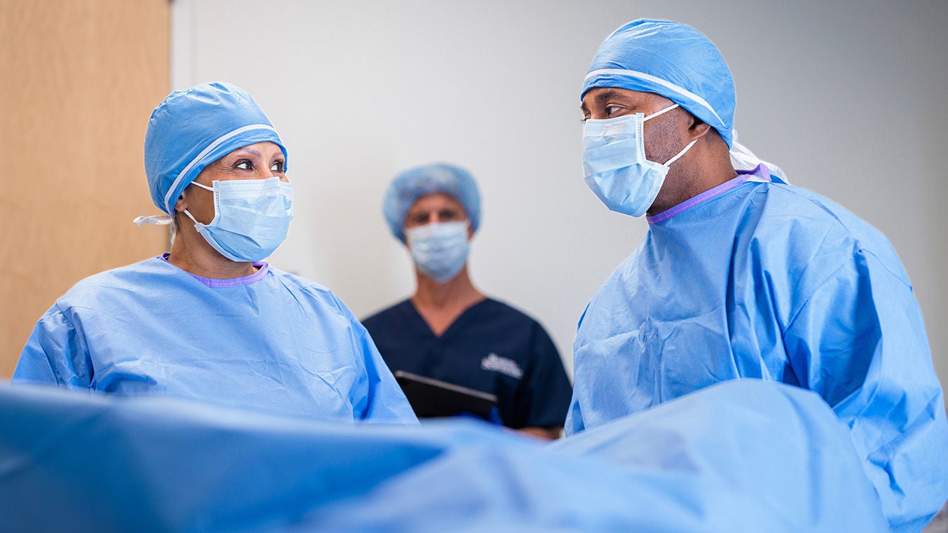 Surgical team in masks and gowns performing a procedure for benign prostatic hyperplasia (BPH).