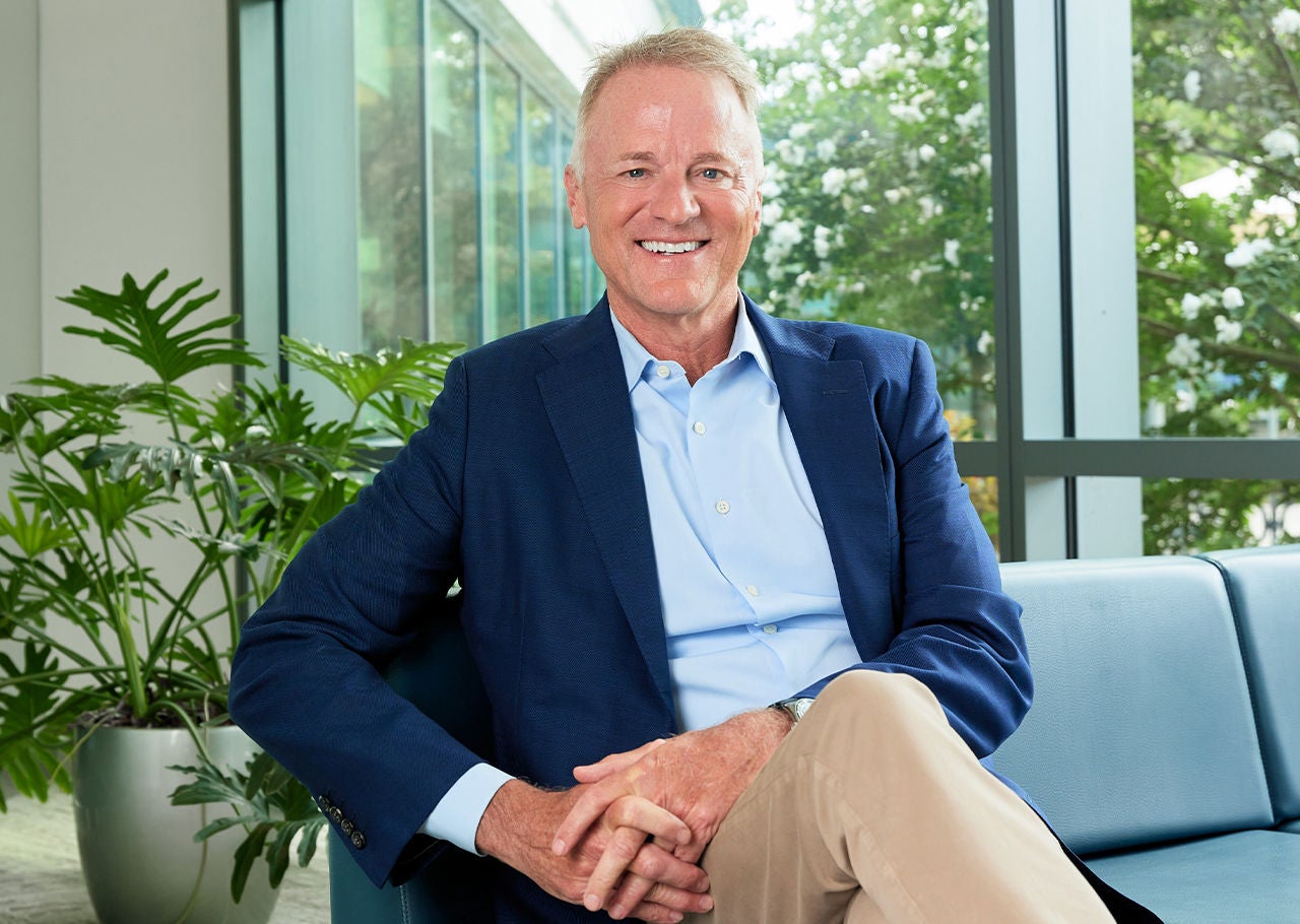 Mike Mahoney Boston Scientific Chairman and CEO smiling and sitting on sofa.