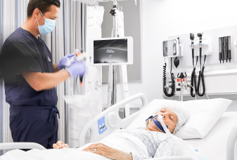 Hand in purple medical glove holding EXALT Model B Single-Use Bronchoscope.