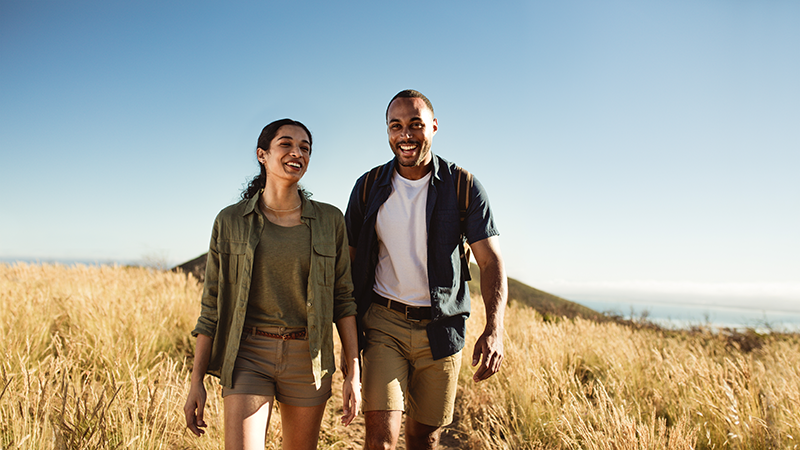 Couple hiking on grassing hillside.