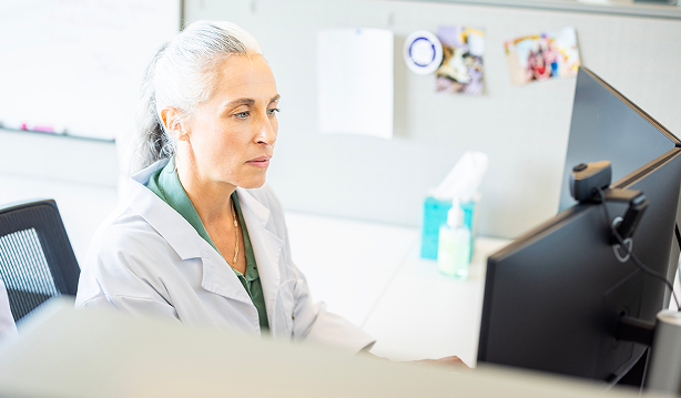 Healthcare provider reading from computer screen.