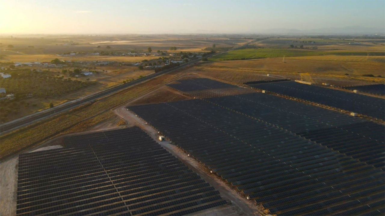Drone shot of solar plant in open area.