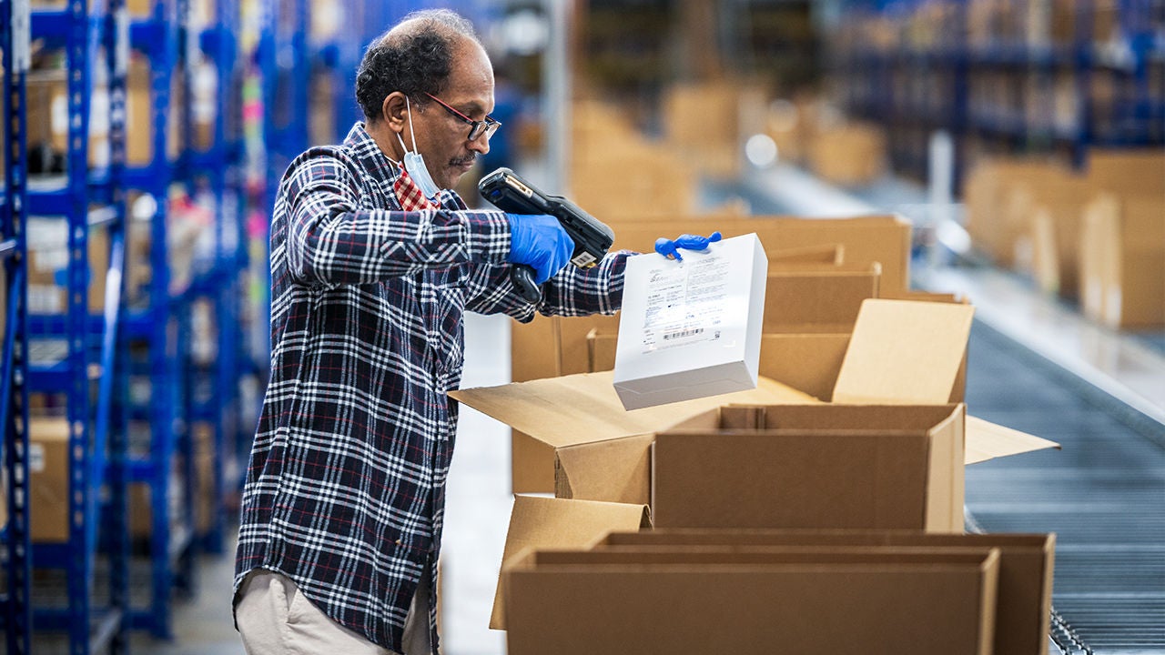 Warehouse employee packaging products and team members attending a meeting.