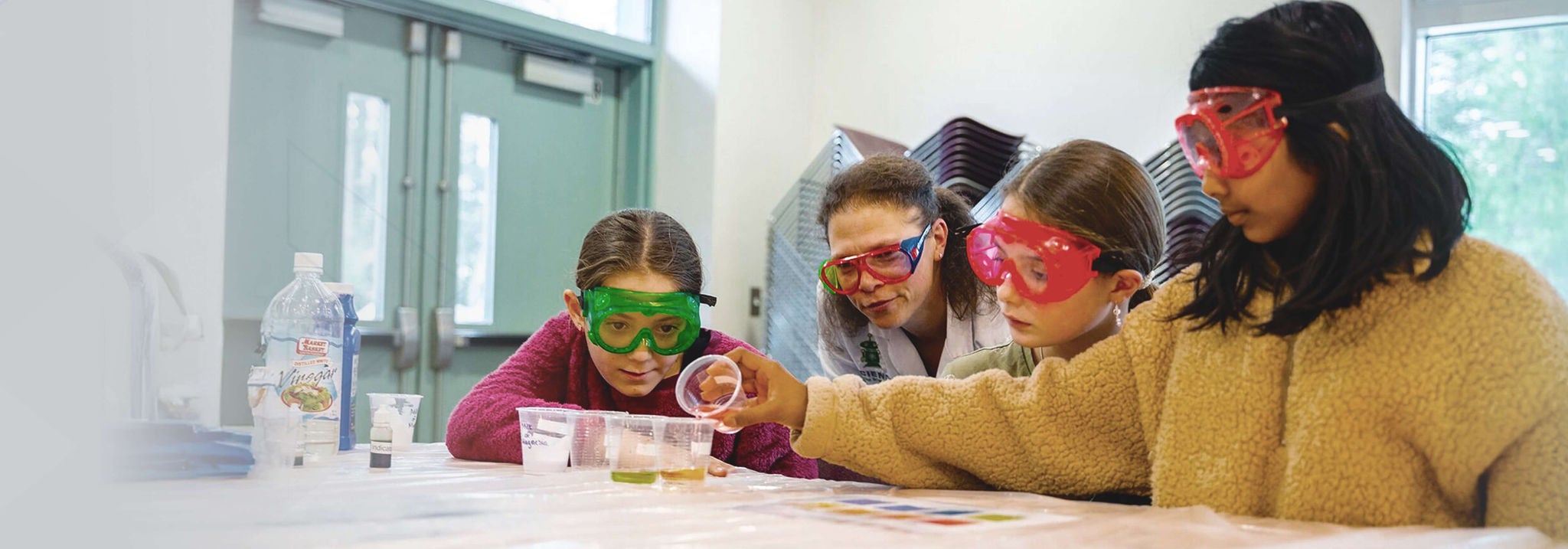 Students doing scientific experiment with teacher inside the lad with protective glass.