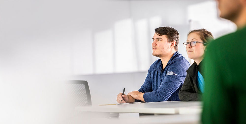 Two Boston Scientific employees sitting at the table watching a seminar