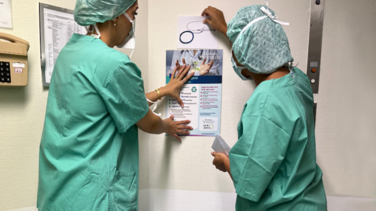 Two female physicians hang boston scientific's sustainability project materials on a wall 