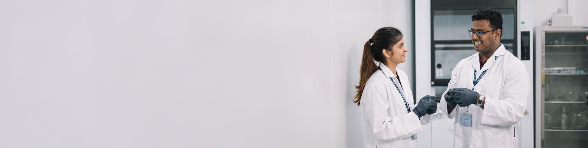 A woman and a man wearing Boston Scientific lab coats talk to each other.