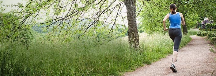 Woman exercising by running on a path in the outdoors.