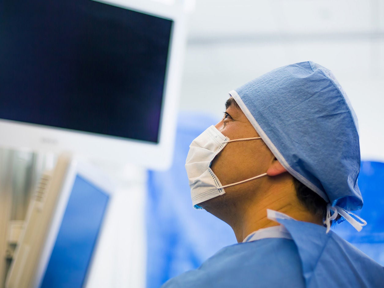 Surgeon looking at a medical monitor in an operating room.