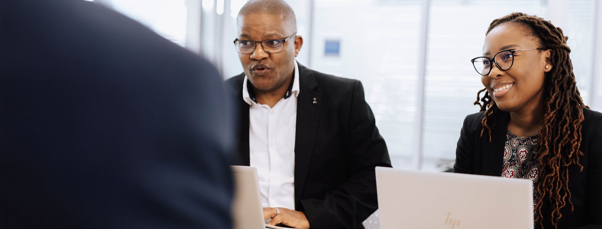 Smiling black men and women in front of laptop and doing discussion .