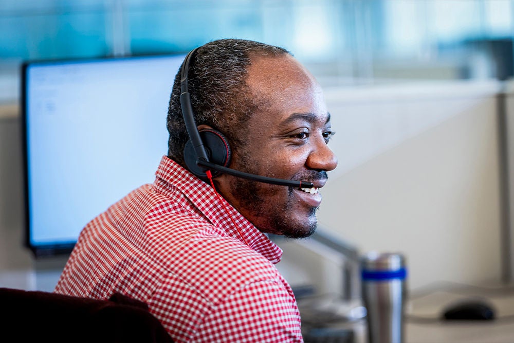 Customer service representative wearing a headset and assisting customers from a workstation.