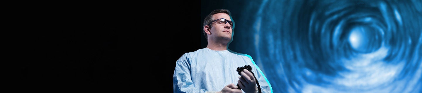 physican holding medical device in mask and lab coat.