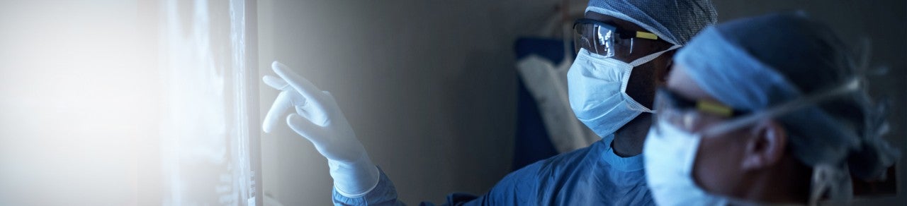 Image of surgeon and tech looking at a screen in a dark surgery room