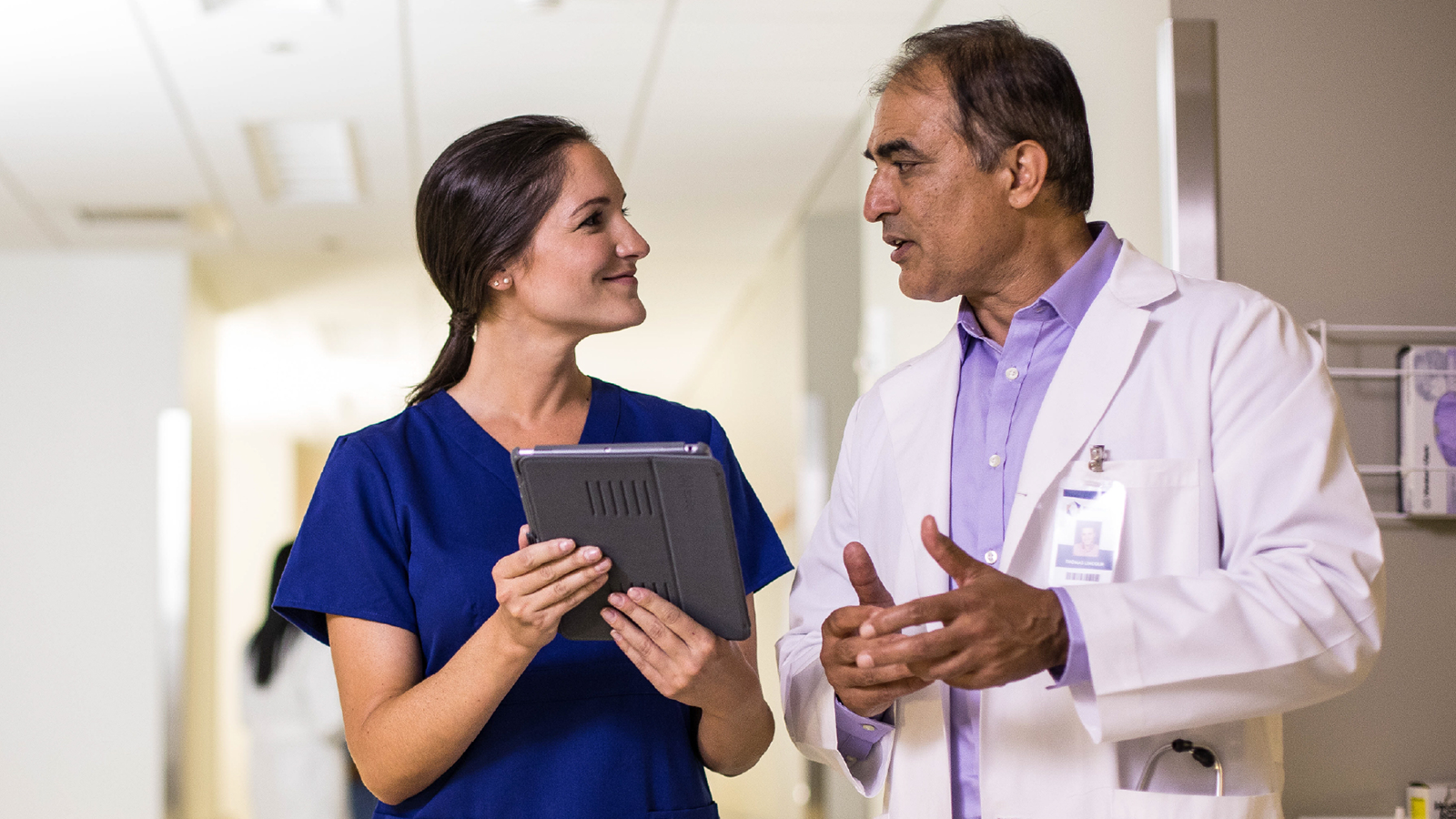 Healthcare provider discussing while holding tablet.