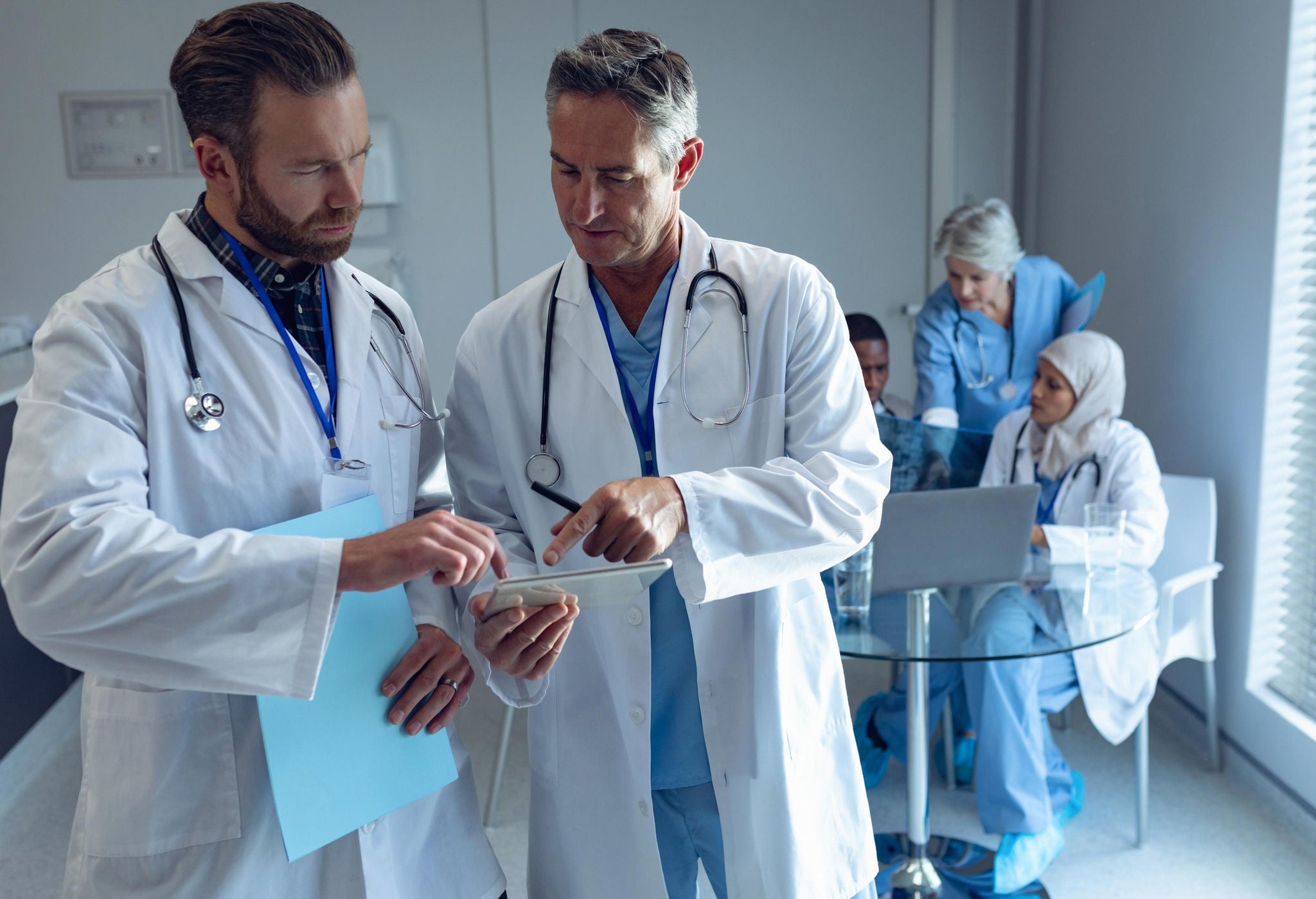 Doctor talking to other doctor in office with team in the background